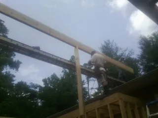 Carpenter setting a ridge beam over a new addition frame — Ice Dam Removal by Roofing Brothers in Bon Air