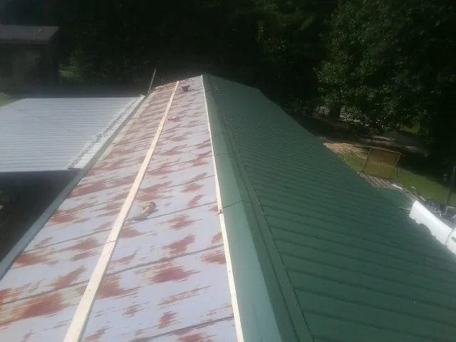 Old rusted panels beside newly installed green metal roofing — Wind Damage Roof Repair by Roofing Brothers in Bon Air