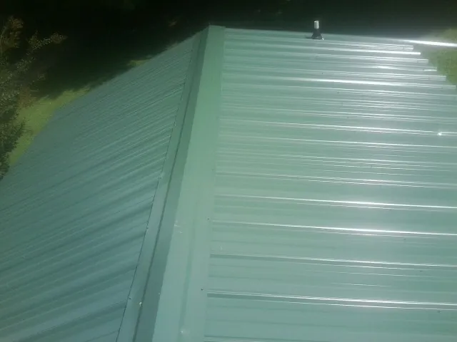 New green metal panels meeting at the ridge of a roof — Flat Roof Repair work by our crew in Bon Air