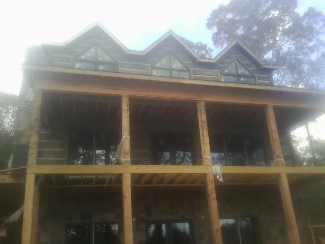 Dormers and porch framing on a large log home under construction — Roof Coating work by our crew in Bon Air