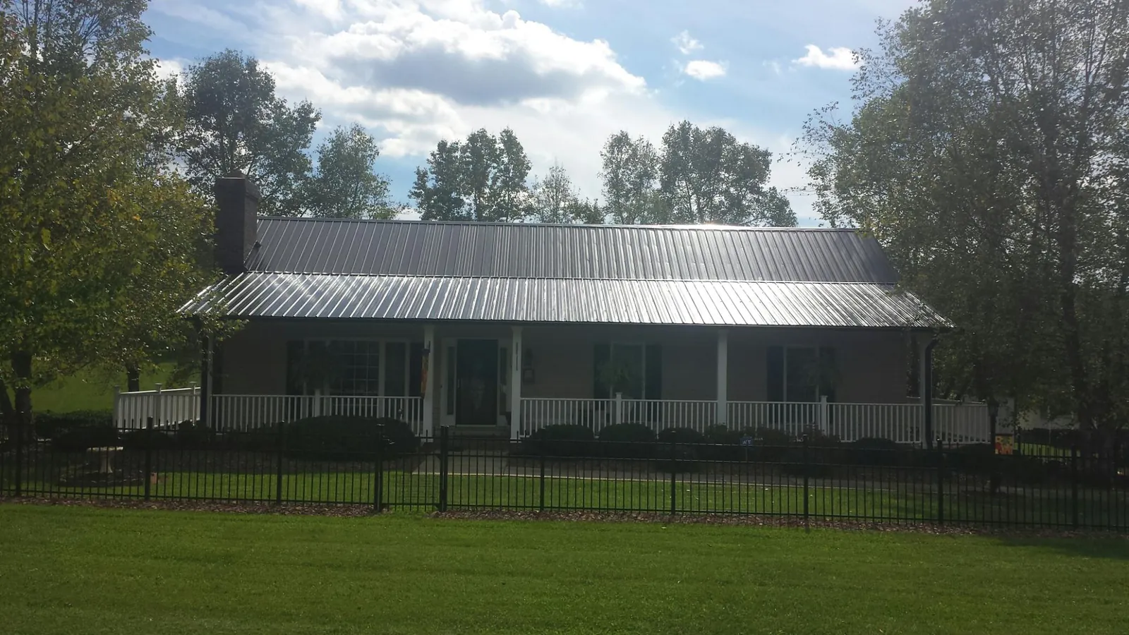 Gray metal roof on a brick ranch with a full width front porch — Gutter Guard Installation work by our crew in Bon Air