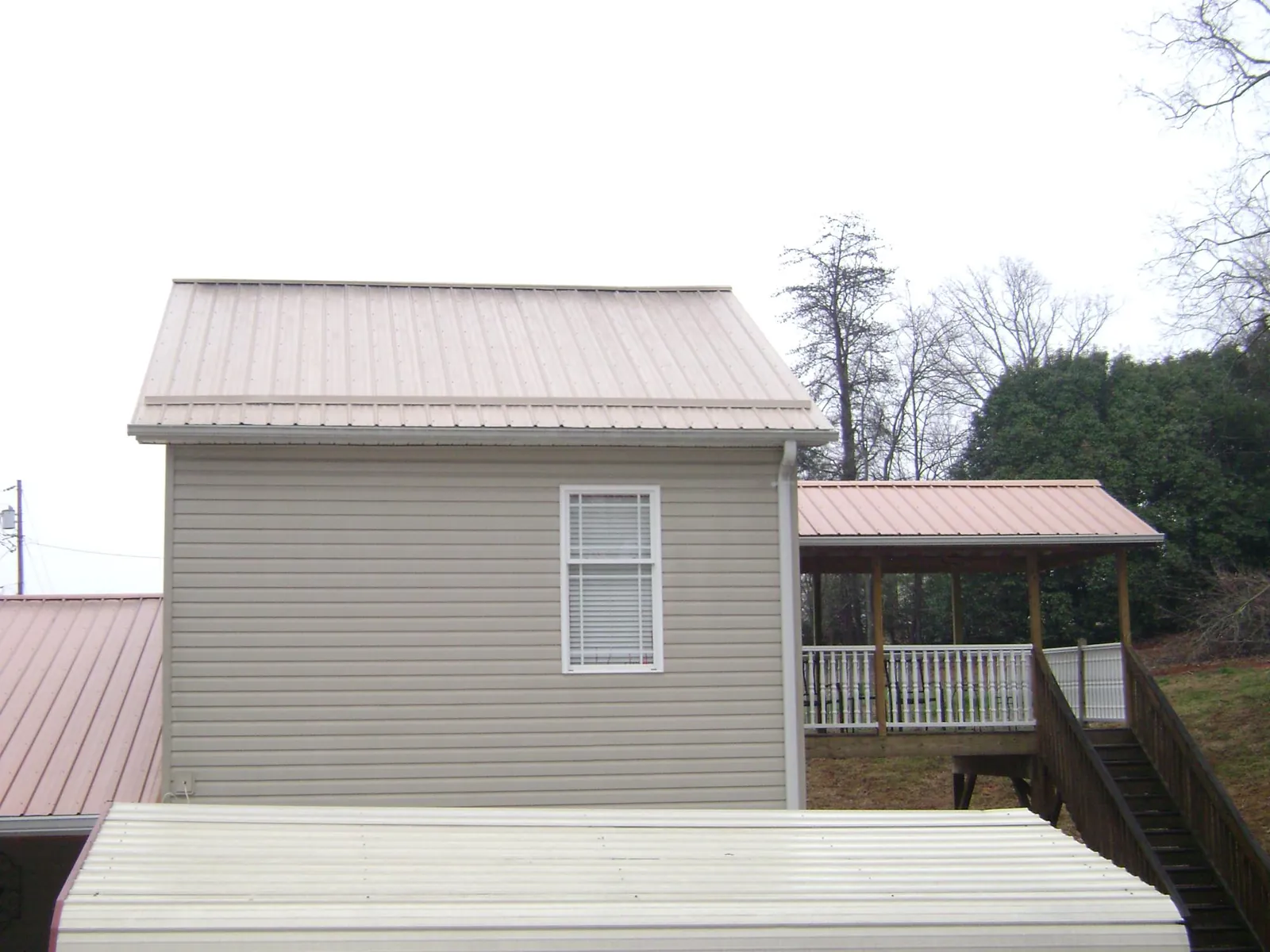 Tan metal roofs on a two story addition and attached porch, from a Roof Replacement job in Bon Air