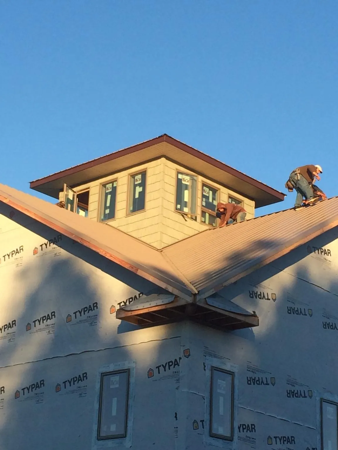 Roofers working around a rooftop cupola on a new metal roof at sunset — Roof Waterproofing in Bon Air by Roofing Brothers